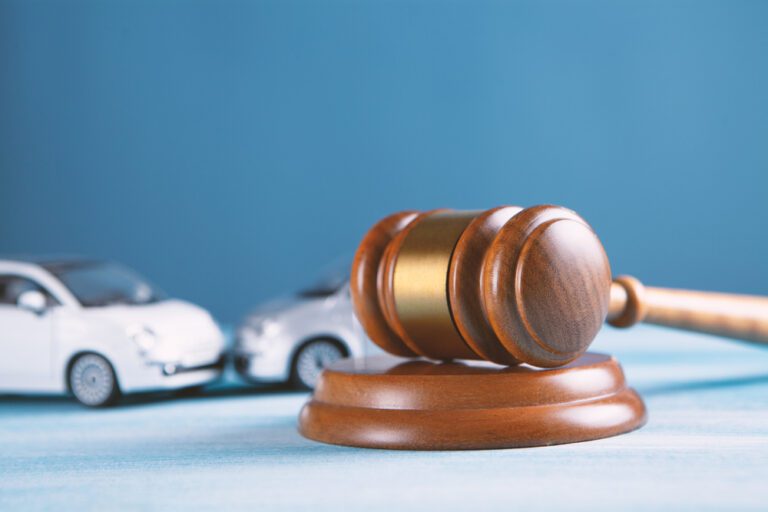 A judge's gavel in front of miniature cars, symbolizing legal issues related to cars or auto law.