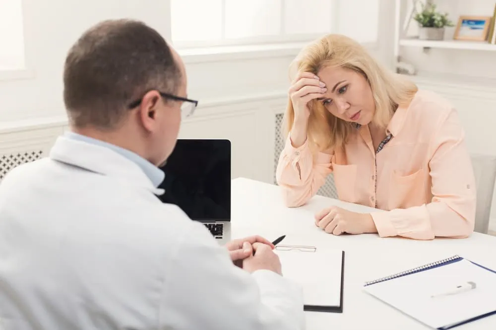 Female patient discusses health concerns with doctor. Medical consultation concept with space for text.