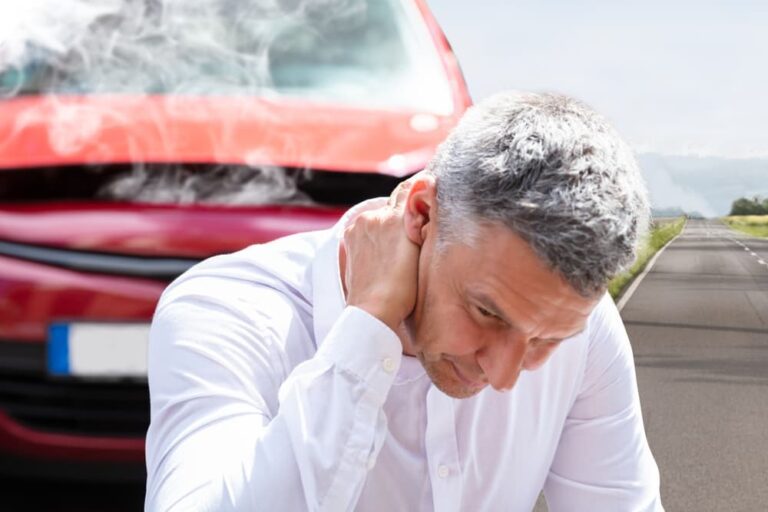 A mature man experiencing neck pain near a broken down car.