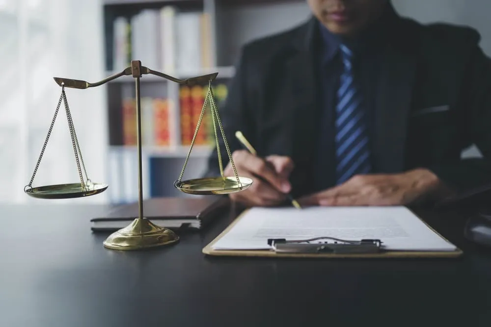 A lawyer reviewing contract papers with a wooden gavel on a courtroom table. Concept of justice, law, attorney, and court judge.