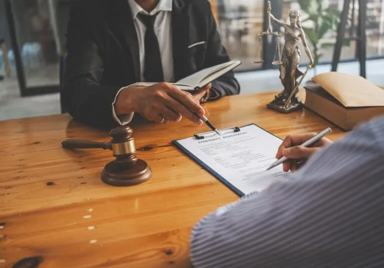 A close-up of a judge's gavel with a professional lawyer discussing a lawsuit in the background. Legal professionals deliberating on a legal case.