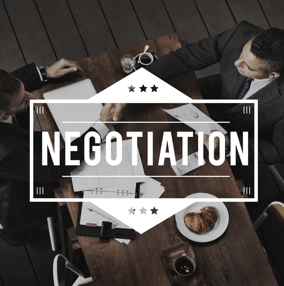 Two individuals engaging in contract agreement negotiation, working to make a mutually beneficial deal.