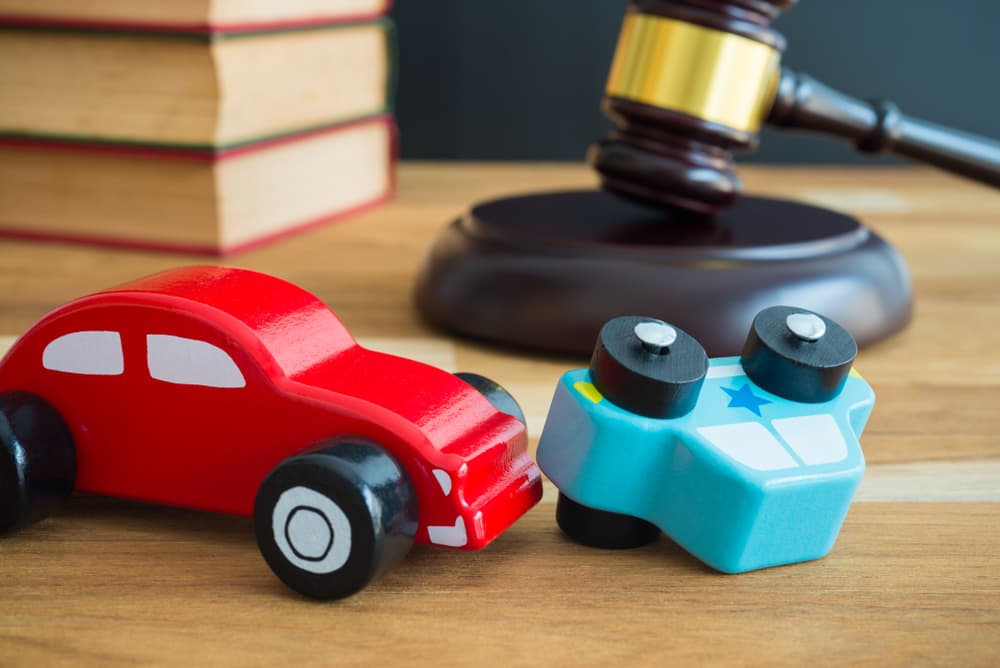 Concept of car accident, auto insurance, and legal judgment represented by a judge's gavel. 