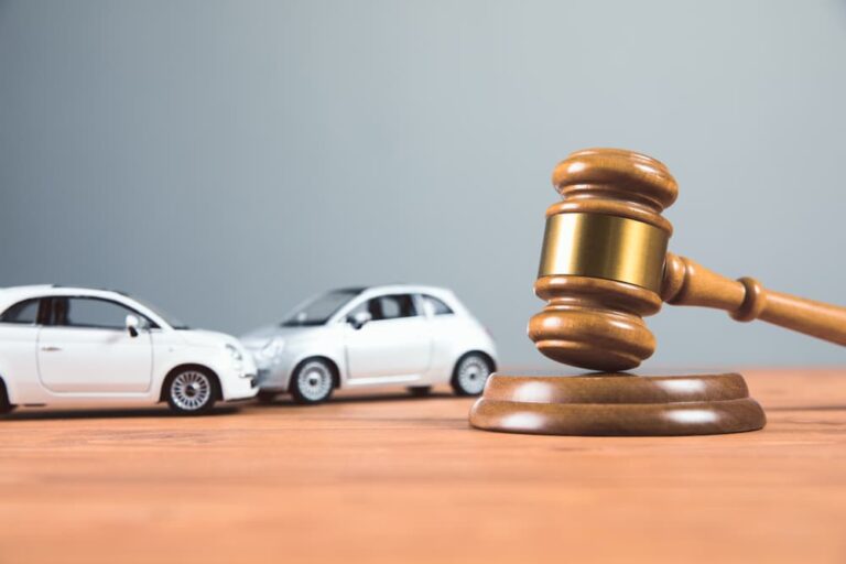 Gavel on table next to toy cars symbolizing a legal case or judgment related to a car accident.