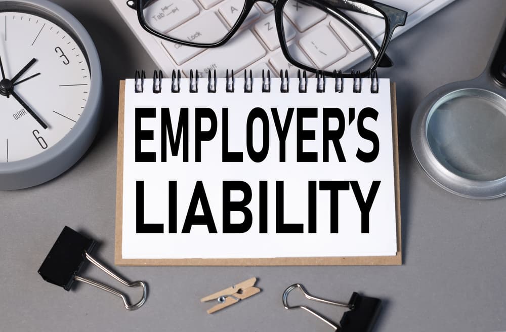 Create a business concept image featuring the text "Employer's Liability" displayed in a notepad format against a gray background.