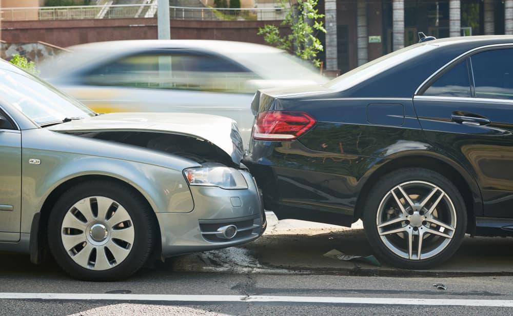 Automobile collision on the street results in vehicle damage. 