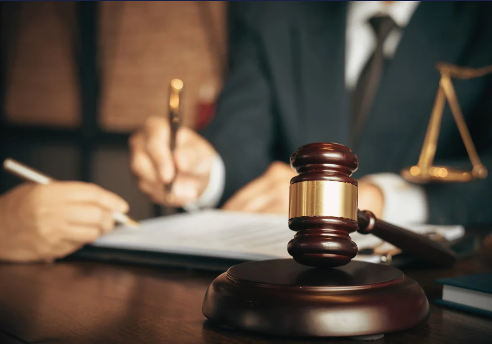 a car accident lawyer goes over paperwork with a new client, there is a gavel in the forefront of the image representing justice