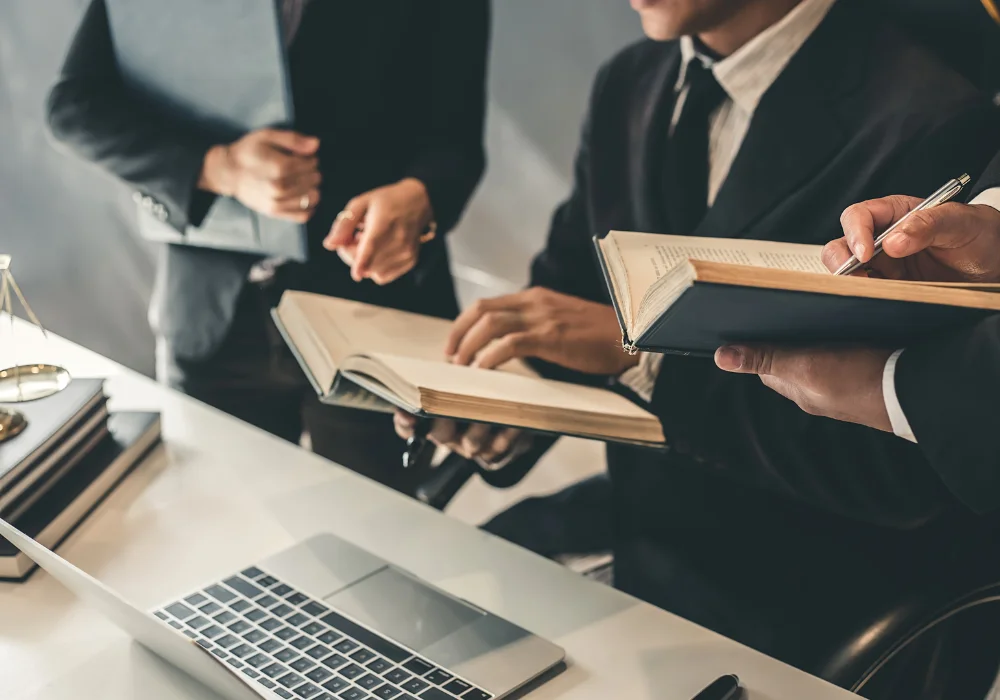 suited injury lawyers research state litigation laws, holding books near an open laptop 