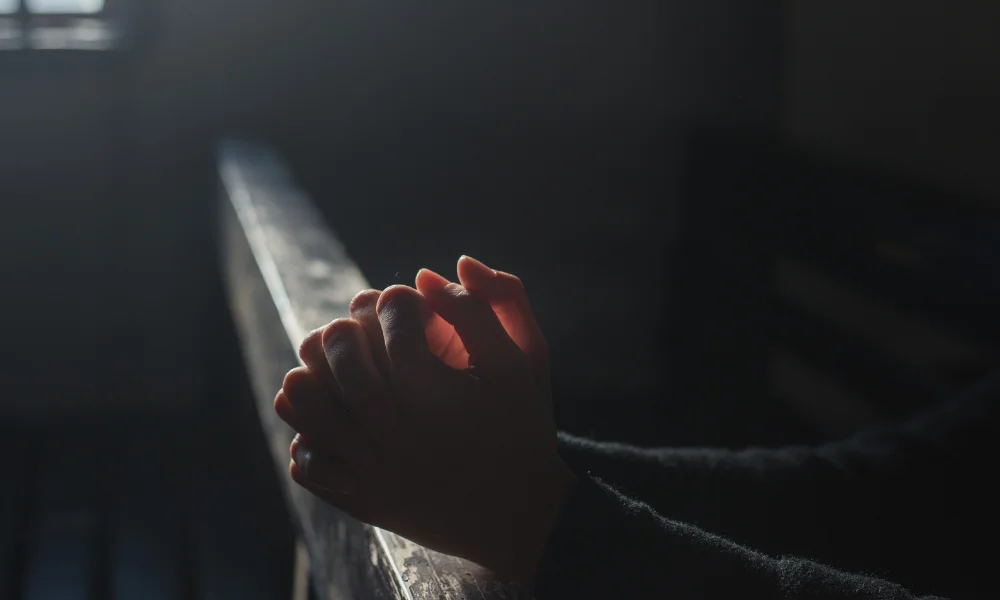 a pair of hands pray in a low lit room