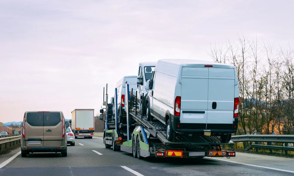 Un camión comercial grande con remolque comparte la autopista con una camioneta familiar.