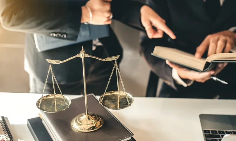 a lawyer wearing a suit shares information with a client, perhaps about the settlement