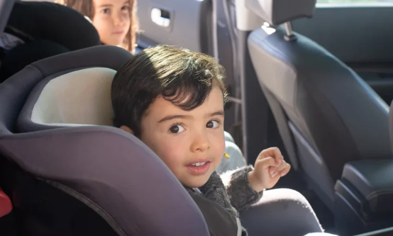un niño pequeño se sienta en un asiento elevado para el automóvil y mira el punto de vista de la cámara
