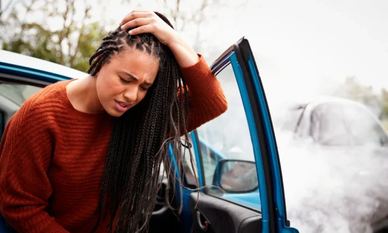Una mujer sostiene su cabeza herida después de un accidente automovilístico.