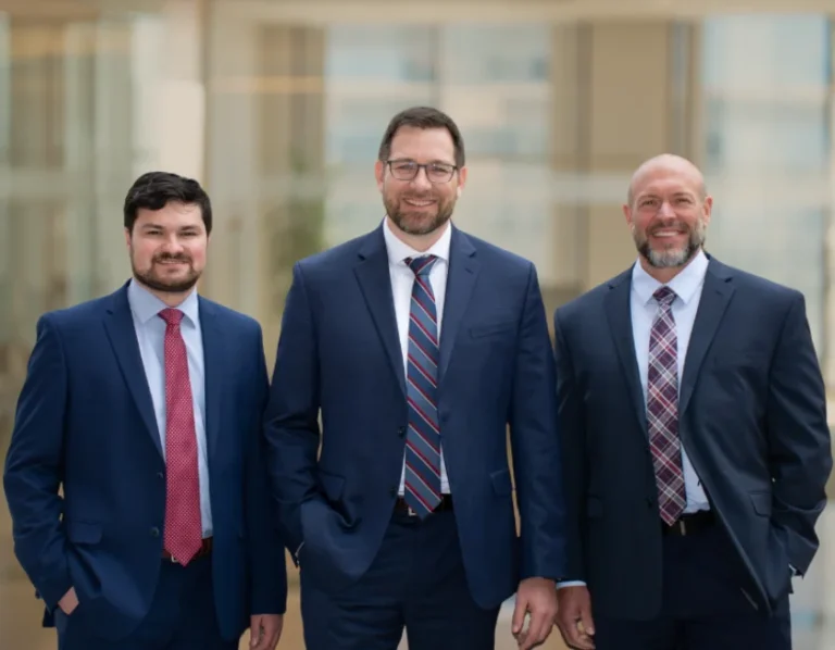 Wisconsin Personal Injury Lawyers from Pemberton wear suits and smile with a gold-hazed office in the background