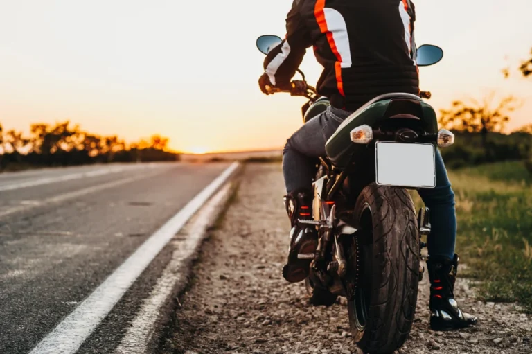 Motorcycle rider parked on the side of the road, looks ahead and is about to ride