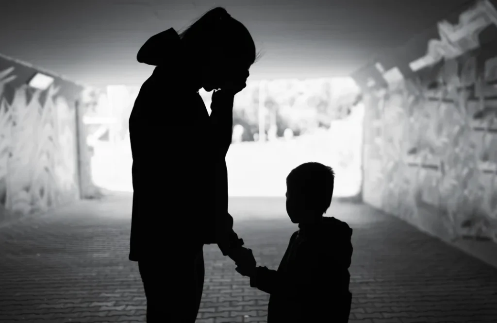 A silhouette of a parent and their child, the parent appears to be sad, as if grieving
