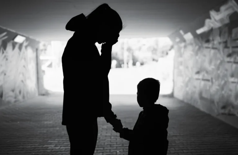 A silhouette of a parent and their child, the parent appears to be sad, as if grieving