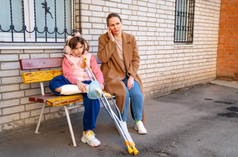 A parent with their injured child on a park bench make a phone call to file a claim within the statute of limitations