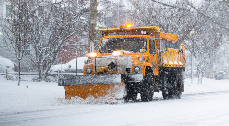 A towns yellow snowplow trying to clear the roads with heavy snowfall making it very difficult in Babylon Long Island in Early 2021.