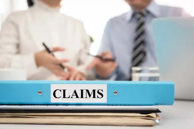 Legal discussion on insurance claim policy with claims document folder in meeting room.