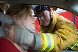 firefighter assists a woman with a neck brace after a car accident causes an injury